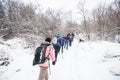 Hikers with backpack hiking on snowy trail. Group of people walking together at winter day. Back view Royalty Free Stock Photo