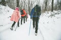 Hikers with backpack hiking on snowy trail. Group of people walking together at winter day. Back view