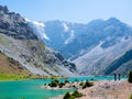 Hikers with backpack near Kulikalon lake on rocky mountain background. Fann Mountains, Tajikistan, Central Asia