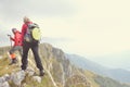 Hikers with backpacks relaxing on top of a mountain and enjoying the view of valley Royalty Free Stock Photo