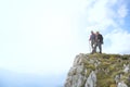 Hikers with backpacks relaxing on top of a mountain and enjoying the view of valley Royalty Free Stock Photo