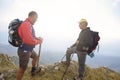 Hikers with backpacks relaxing on top of a mountain and enjoying the view of valley Royalty Free Stock Photo