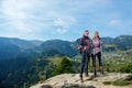 Hikers with backpacks relaxing on top of a mountain and enjoying the view of valley Royalty Free Stock Photo