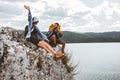 Hikers with backpacks and their doberman sitting on cliff enjoying at the mountain lake