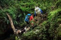 Hikers climb up a forest path with the help of a rope