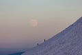 Hikers climbing a mountain summit at sunset with a moonrise behind (Pen-y-Fan, Brecon Beacons Royalty Free Stock Photo