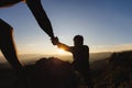 Hikers climbing up mountain cliff and one of them giving helping hand. People helping and, team work concept Royalty Free Stock Photo