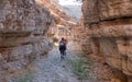 Hikers on a hiking trail inside a dry canyon in a remote desert region.