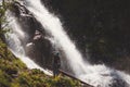 Hikers man backpacker looking at a waterfall in the forest.