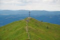 Hikers near big metal cross in Carpathian Mountains in Ukraine