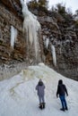 Hikers near frozen Awosting Falls, massive icicles hang from the cliffs in Minnewaska State Park in Upstate New York. USA