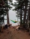 Hikers relaxing in hammock between two pine trees overlooking Joffre Lake, BC, Canada