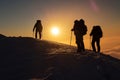 hikers silhouette against the setting sun on a snowy ridge