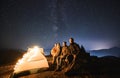 Group of travelers sitting near camp tent under night starry sky. Royalty Free Stock Photo