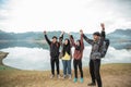 Hikers standing with hands up enjoy lake view