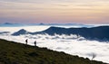 Hikers standing on top of Mount Artxueta in the morning sunrise against the sea of clouds in Aralar