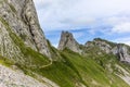 Hikers on the steep path leading to the majestic  Schaefler peak in the  Alpstein mountain range around the Aescher cliff in Royalty Free Stock Photo