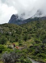 Hikers in Torres del Paine National Park, below fog bound granite peaks