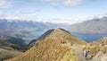 Hikers walking the ridgeline in beautiful alpine landscape with mountains and lake, New Zealand