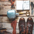 Hiking accessories on wooden background: old hiking leather boots, vintage film camera, travel notebook, knife. Lifestyle concept