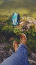 Hiking backpack and legs in sports shoes of young woman resting in a mountain hike in the valley Royalty Free Stock Photo