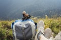 Hiking backpack, trekking poles and legs in sports shoes of young woman resting in mountain hike in valley, active healthy Royalty Free Stock Photo