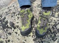 Hiking Boots closeup on the rocky mountain with green forest and lake on the background