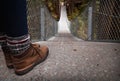 Hiking boots at the top of a suspension bridge in a forest.