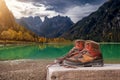 Hiking boots on wooden bench at Landro lake in the Dolomites mountains in Italy. Italian landscape or scenery.