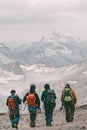 Hiking and climbing. Four tourists with backpacks on the background of a mountain snow-covered ridge