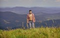 Hiking concept. Man unbuttoned shirt stand top mountain landscape background. Muscular tourist walk mountain hill. Power
