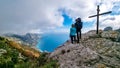 Hiking couple with backpack at summit cross near Santa Maria del Castello with scenic view on Positano Amalfi Coast, Italy