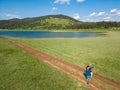 Hiking couple enjoy walking along a trail near blue mountain lake, aerial view Royalty Free Stock Photo