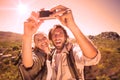 Hiking couple standing on mountain terrain taking a selfie