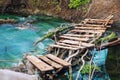 Hiking footpath through scenic beautiful old wooden plank bridge over clean mountain stream with clear turquoise water. Tranquil Royalty Free Stock Photo