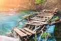 Hiking footpath through scenic beautiful old wooden plank bridge over clean mountain stream with clear turquoise water. Tranquil Royalty Free Stock Photo
