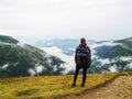 Hiking girl with backpack standing enjoying mountains scenery on rainy day Royalty Free Stock Photo
