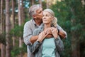 Hiking, kiss and senior couple with love in a forest, relax and hug while standing in nature park together. Caring Royalty Free Stock Photo