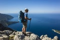 Hiking on Lycian way. Man with backpack standing on rock cliff high above Mediterranean sea enjoying the view Royalty Free Stock Photo