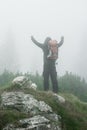 Hiking man with backpack open arms on foggy mountain peak Royalty Free Stock Photo