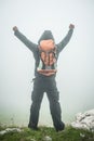 Hiking man with backpack open arms on foggy mountain peak Royalty Free Stock Photo