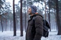 Hiking man with backpack walking in winter foggy forest covered snow. Adventure people in wild nature.