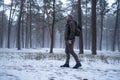 Hiking man with backpack walking in winter foggy forest covered snow. Adventure people in wild nature.