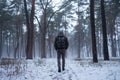 Hiking man with backpack walking in winter foggy forest covered snow. Adventure people in wild nature.