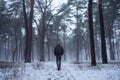 Hiking man with backpack walking in winter foggy forest covered snow. Adventure people in wild nature.