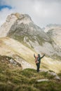 Hiking man with backpacker open arms looking mountain peaks Royalty Free Stock Photo