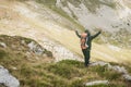 Hiking man with backpacker open arms looking mountain peaks Royalty Free Stock Photo