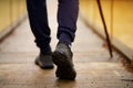 Hiking man crossing river in walking in balance on hinged bridge in nature landscape. Closeup of male hiker trekking