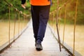 Hiking man crossing river in walking in balance on hinged bridge in nature landscape. Closeup of male hiker trekking