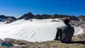 Hiking man sitting at cliff edge. Scenic view on Hoher Sonnblick glacier in High Tauern mountains in Carinthia, Salzburg, Austria